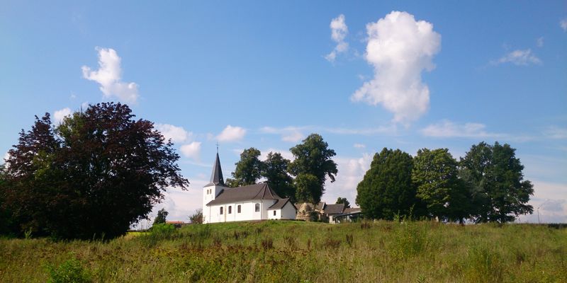 Het witte Clemenskerkje in Brunssum, vanuit de weide er omheen gefotografeerd