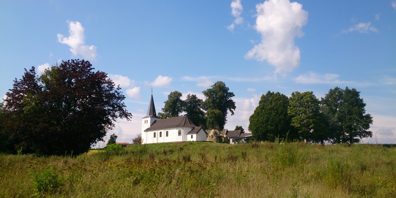 Het witte Clemenskerkje in Brunssum, vanuit de weide er omheen gefotografeerd